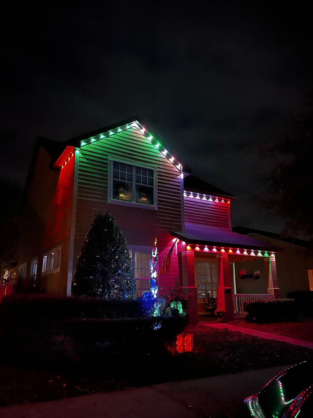 Home with red, green and white permanent Christmas lighting at night