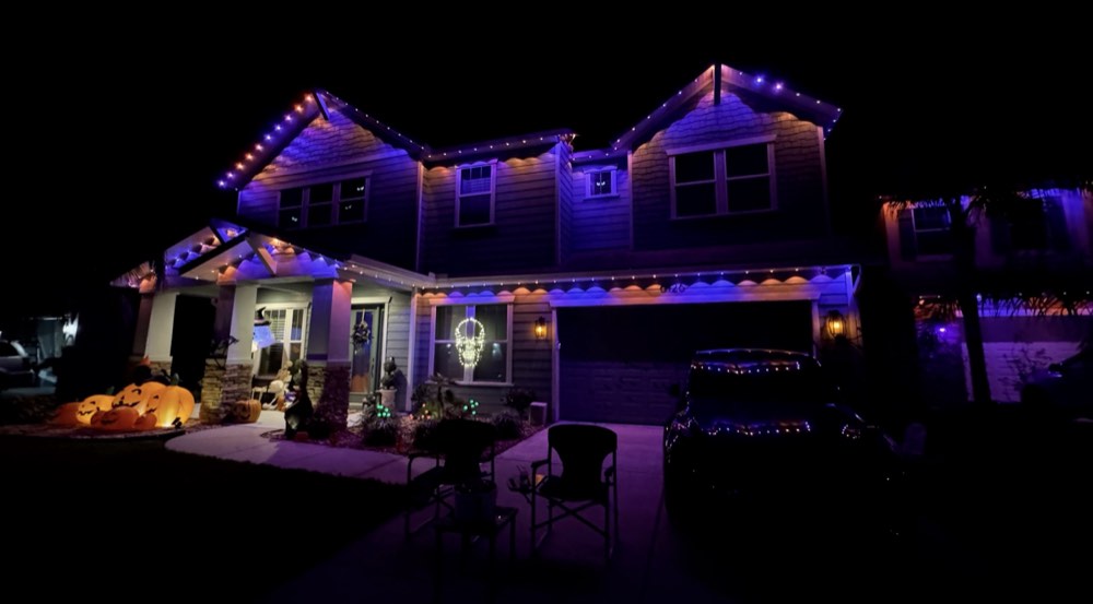 Two-story home in purple and orange Halloween lighting